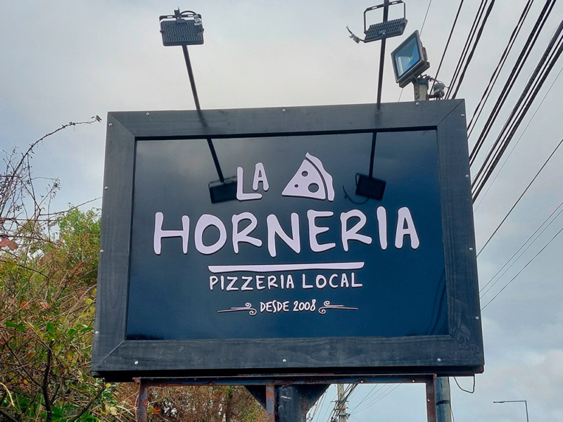 La Hornería — Letrero de alucom negro con logo volumétrico, instalado en estructura existente.