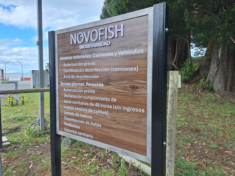Novofish — Letrero de Alucom revestido con lamina HPL diseño madera, con logotipo volumétrico de PVC espumado, textos en vinilo adhesivo y borde de acero inoxidable