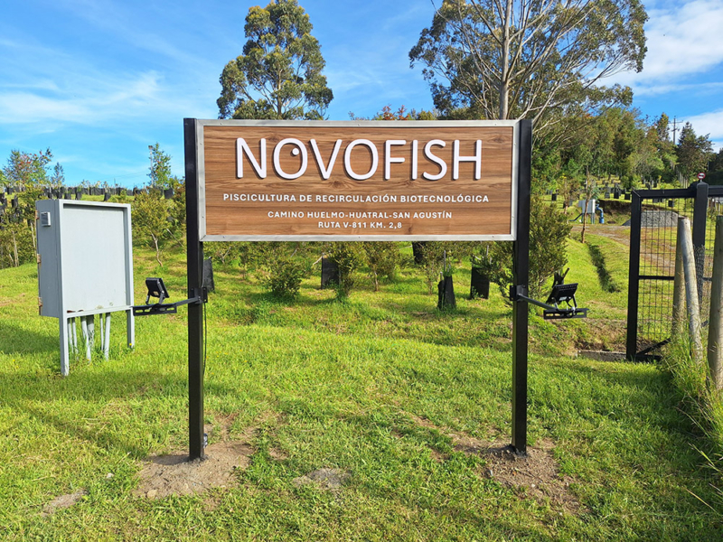 Novofish — Letrero de Alucom revestido con lamina HPL diseño madera, con logotipo volumétrico de PVC espumado, textos en vinilo adhesivo y borde de acero inoxidable