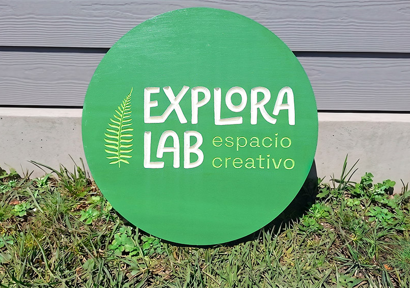 Explora Lab — Letrero circular tallado en pino