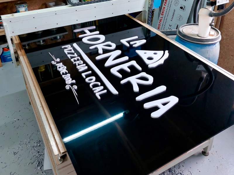 La Hornería — Letrero de alucom negro con logo volumétrico, instalado en estructura existente.