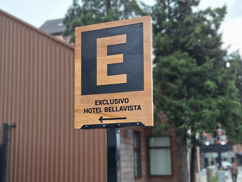 Hotel Bellavista — Letrero entrada estacionamiento exterior. Mañio tallado.